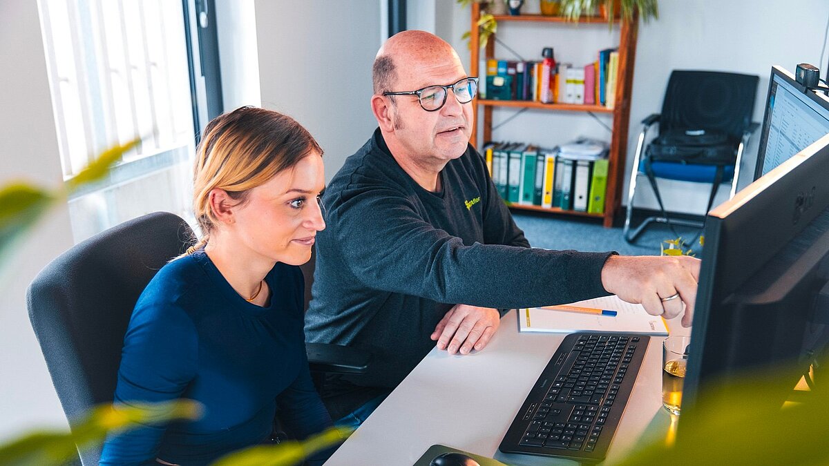 Zwei Dataflor Mitarbeitende arbeiten gemeinsam an einem Computer