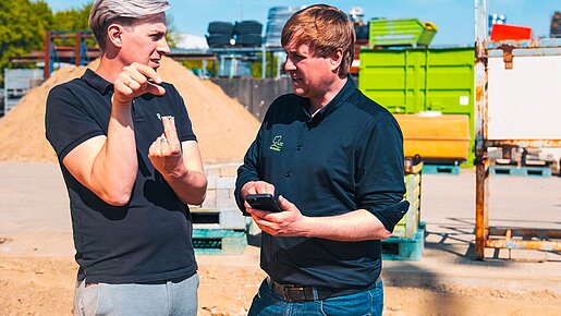 Zwei Personen besprechen digitale Projektdaten auf einer Baustelle